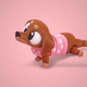 3D-gedruckte Printimon-Figur: kleiner brauner Dackel mit großen Kulleraugen und rosa Punkteshirt auf rosa Hintergrund.